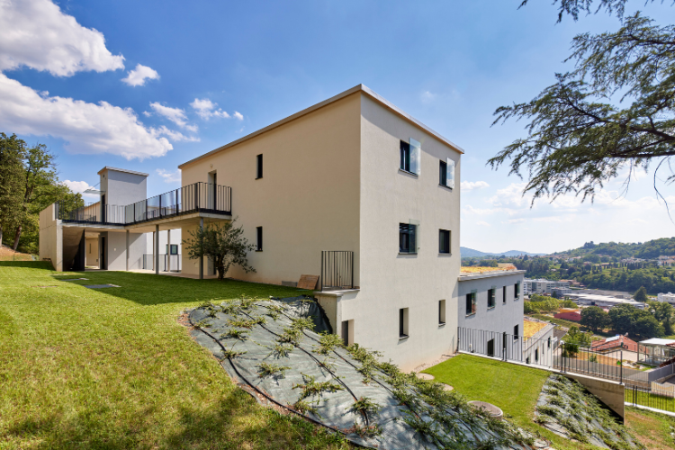 Moderno edificio residenziale in posizione collinare con area verde curata e vista sui dintorni.