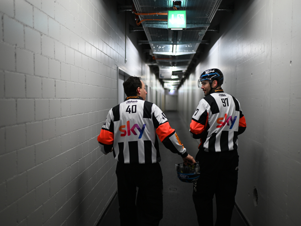 Zwei Eishockeyschiedsrichter des SHIF in Uniform auf dem Weg zu einem Spiel