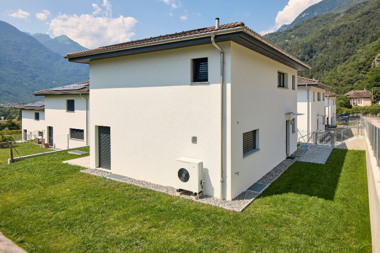Luft/Wasser-Wärmepumpe an der Aussenwand eines modernen Wohnhauses mit Garten. 