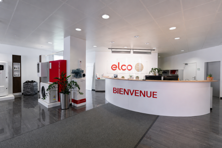 Espace d’accueil ELCO avec logo, comptoir de réception et systèmes de chauffage exposés.