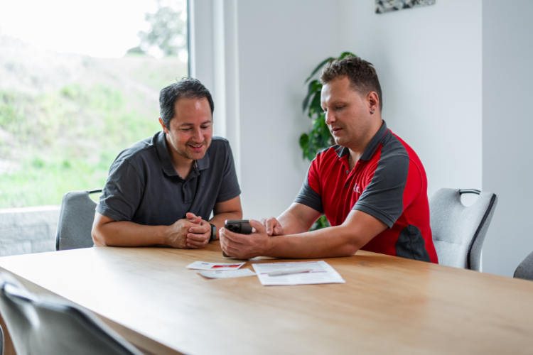 Un technicien ELCO et un client consultent ensemble l’application REMOCON NET sur un smartphone.