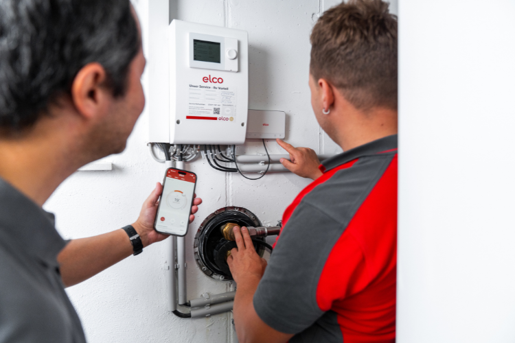 ELCO Servicetechniker zeigt die REMOCON NET App auf einem Smartphone zur Steuerung der Heizung.