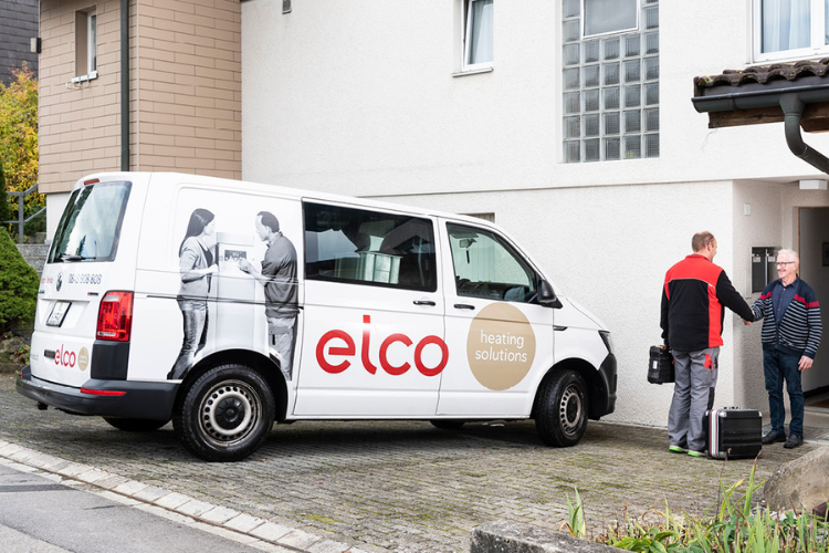 ELCO Servicetechniker kommt mit dem Servicefahrzeug zur Wartung einer Heizungsanlage und begrüsst den Kunden.