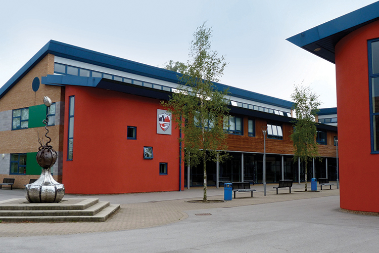 Exterior view of Ripley Academy building with red and brown facade, windows, and sculpture