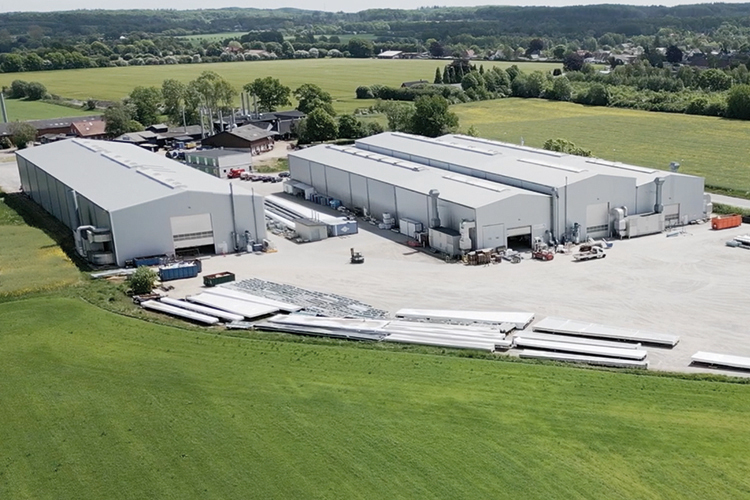 Aerial view of Dencam industrial facility with warehouses, equipment, and surrounding green fields