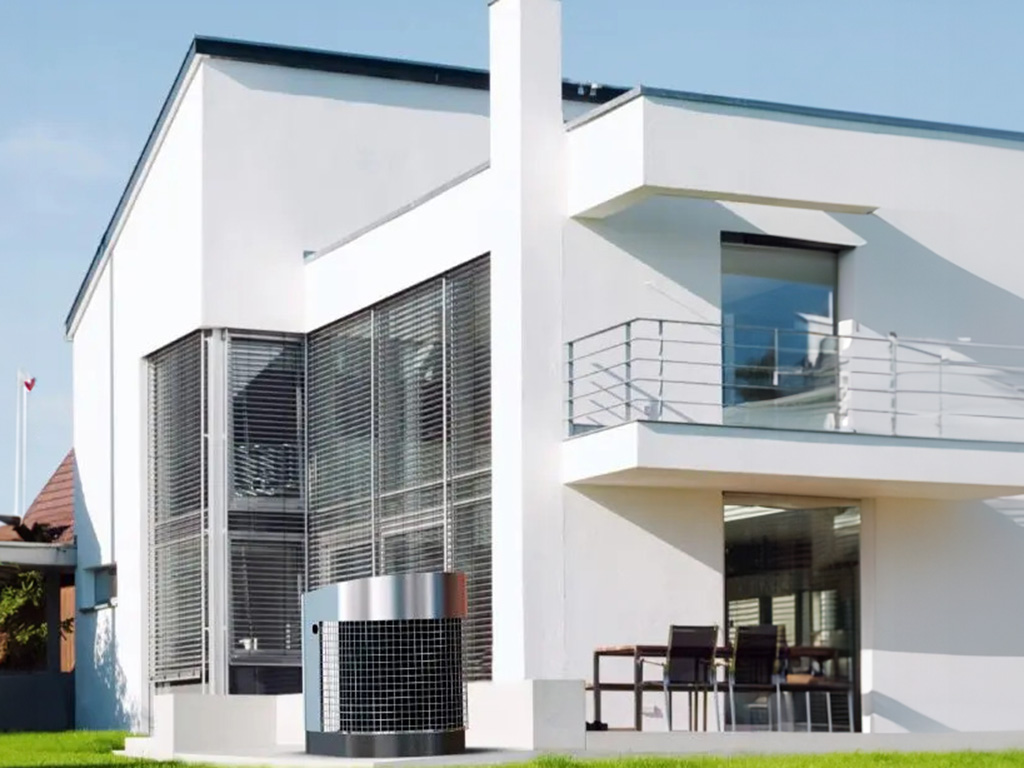Una moderna casa a due piani con ampie finestre e una termopompa installata in giardino